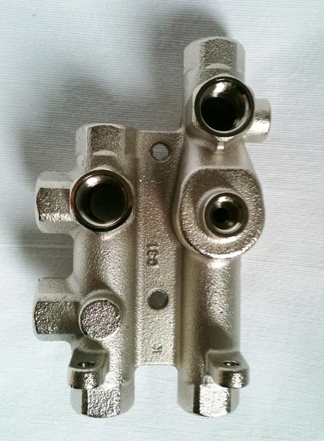 Metallisch silbrig beschichteter Ventilblock aus Guss mit mehreren Gewindeanschlüssen und Sechskantflächen